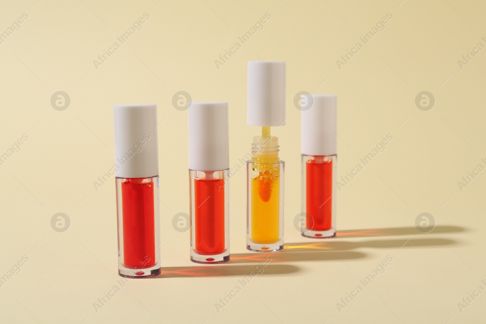 Photo of Many bright lip glosses on beige background