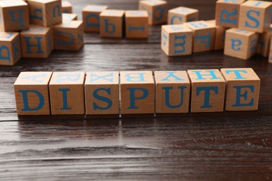 Photo of Cubes with word Dispute on dark wooden table