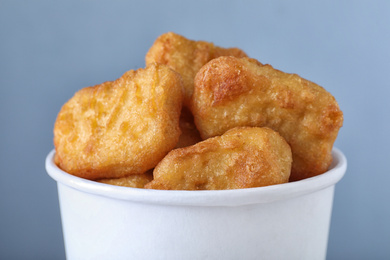 Photo of Bucket with tasty chicken nuggets on blue background, closeup