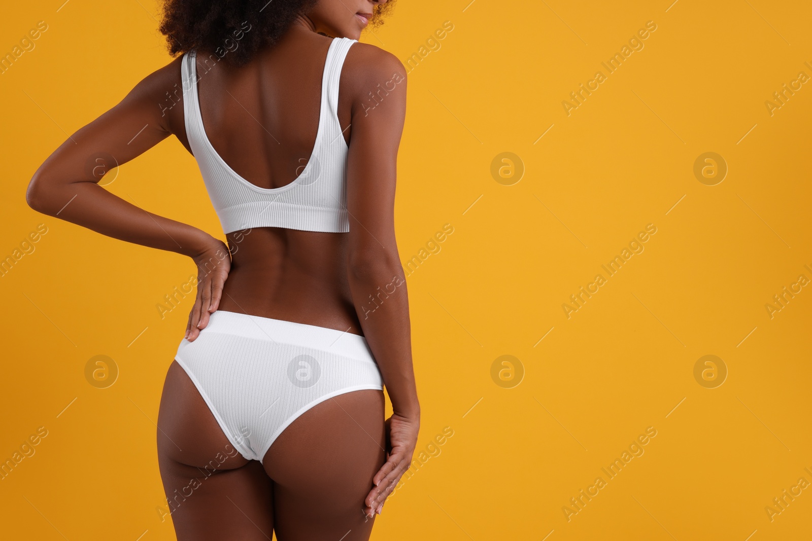 Photo of Woman in stylish bikini on yellow background, closeup. Space for text
