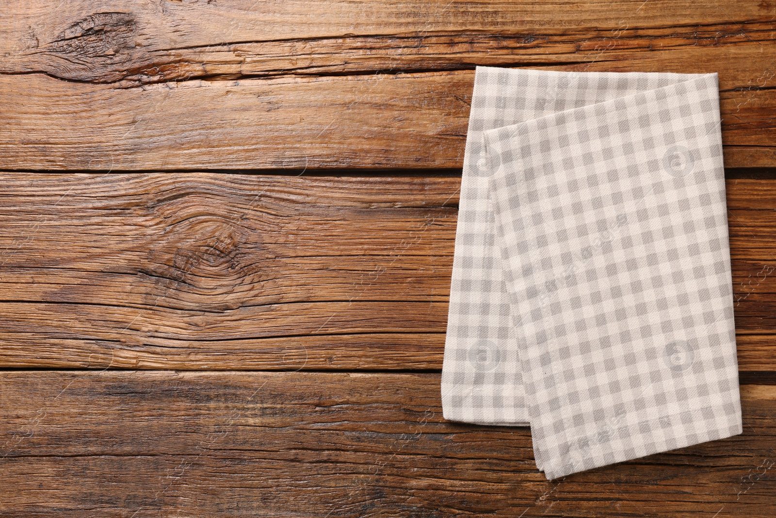 Photo of Beige checkered tablecloth on wooden table, top view. Space for text