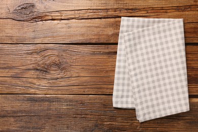 Beige checkered tablecloth on wooden table, top view. Space for text