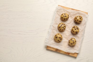 Uncooked chocolate chip cookies on white wooden table, top view. Space for text