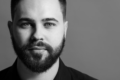 Portrait of handsome bearded man on grey background, space for text. Black and white effect