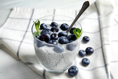 Photo of Tasty chia seed pudding with blueberries in glass on table