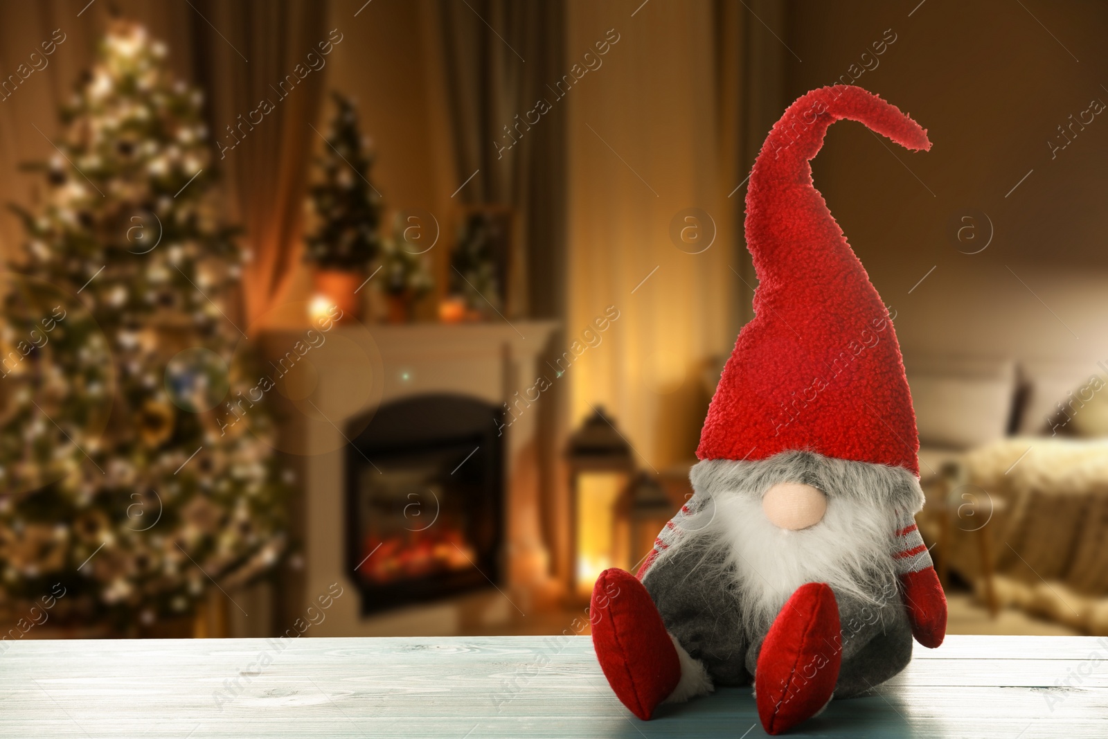 Image of Funny Christmas gnome on turquoise wooden table in room with festive decorations. Space for text