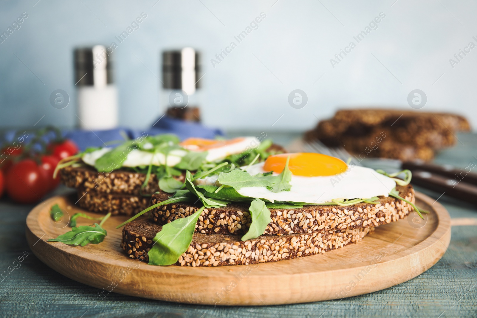 Photo of Delicious sandwiches with arugula and fried egg on blue wooden table