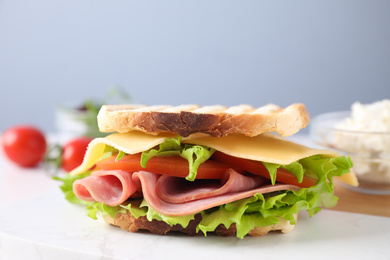 Photo of Tasty sandwich with ham on white marble table, closeup
