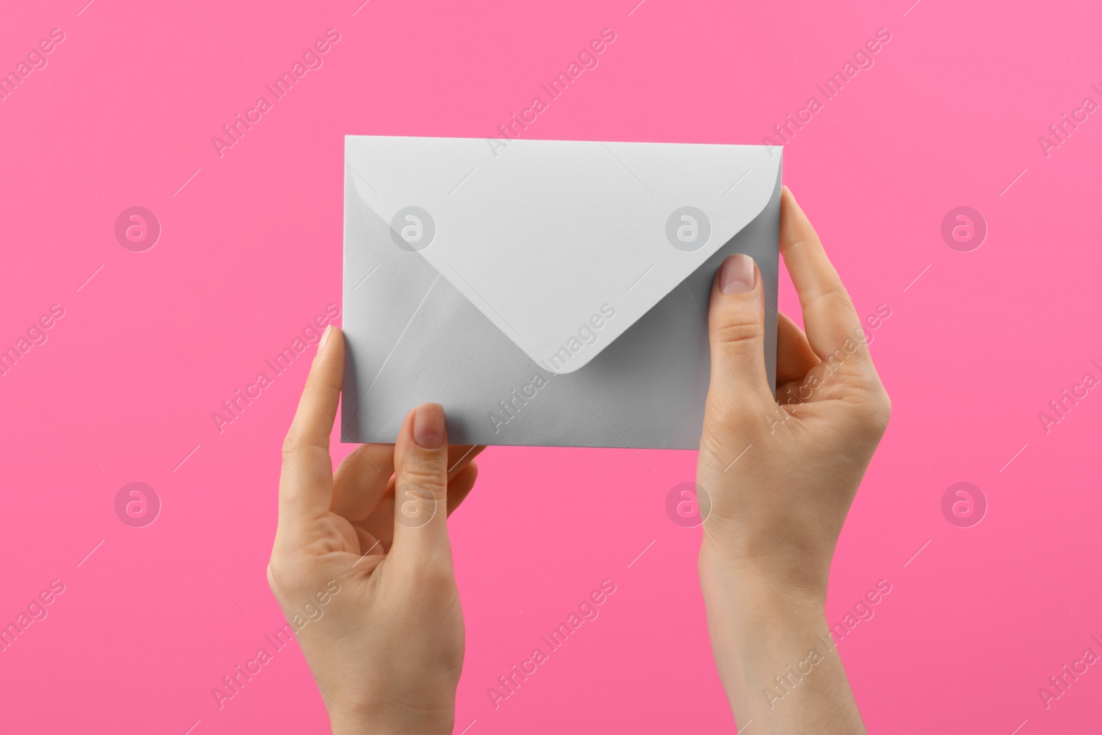 Photo of Woman holding white paper envelope on pink background, closeup