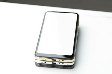 Photo of Stack of modern smartphones on white table