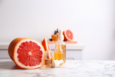 Bottles of essential oil and grapefruit slices on table. Space for text