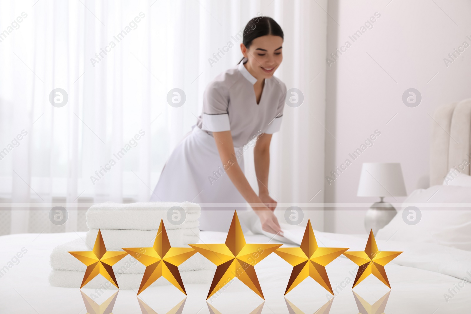 Image of Chambermaid making bed in five star hotel room