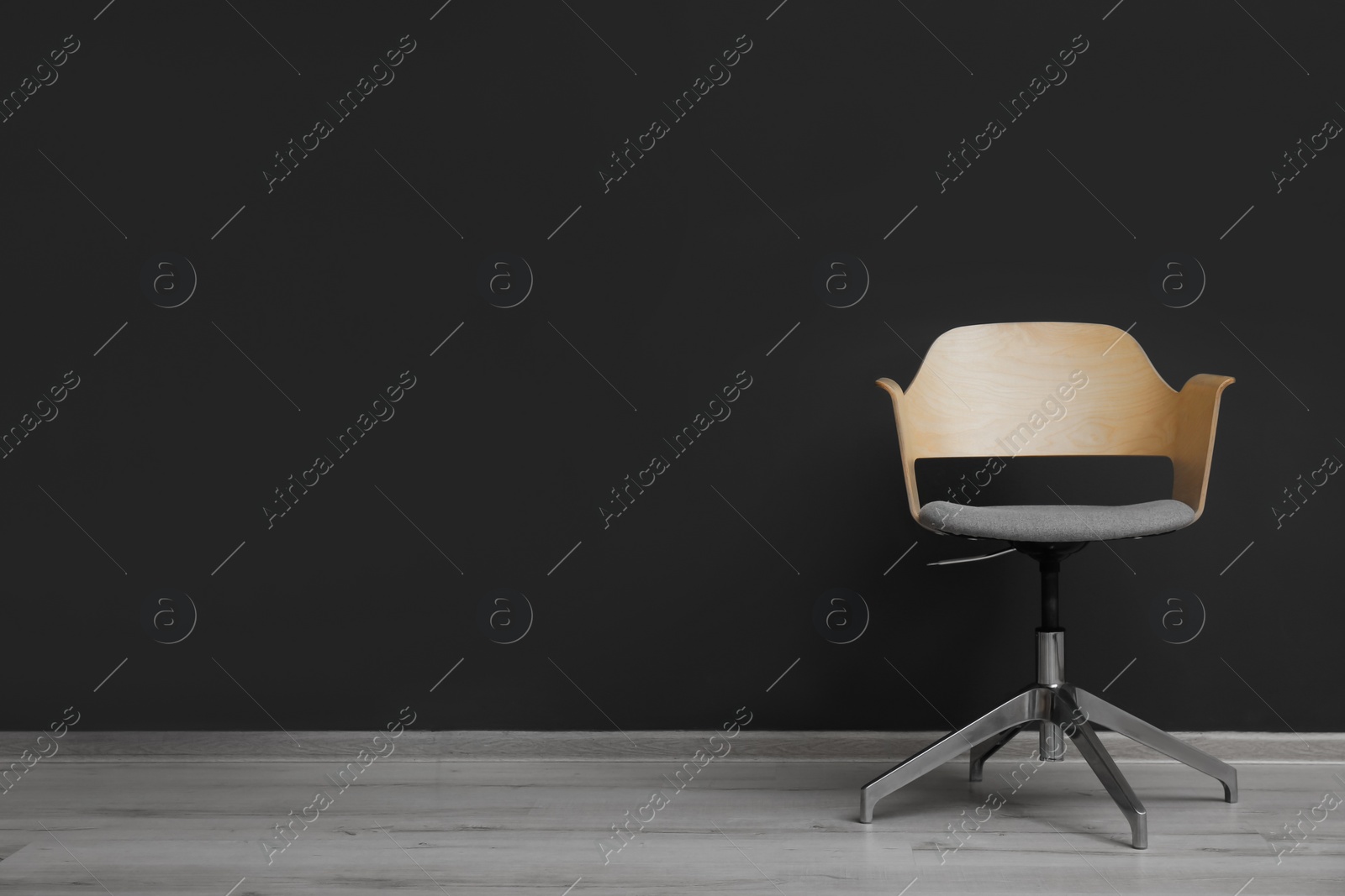 Photo of Comfortable office chair near black wall indoors. Space for text