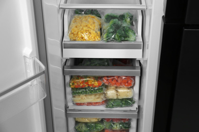 Plastic bags with different frozen vegetables in refrigerator