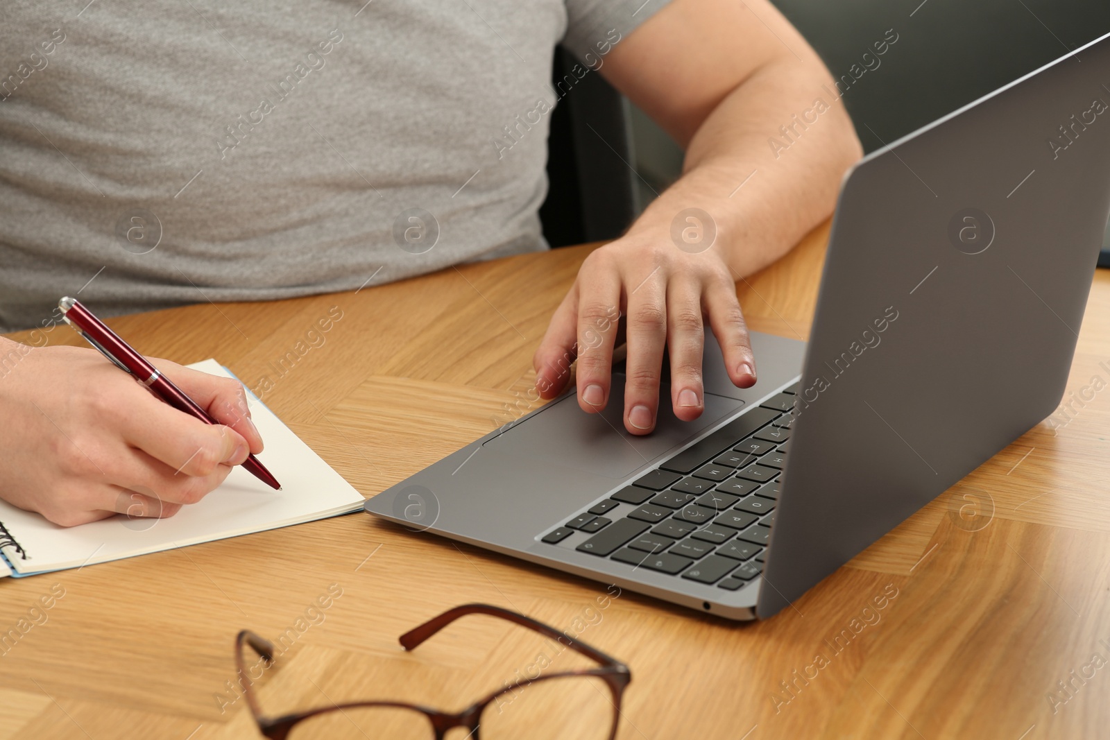 Photo of Man working with laptop at wooden table, closeup