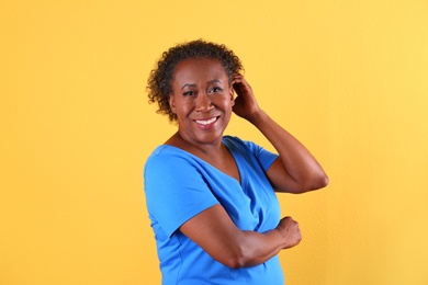 Portrait of happy African-American woman on yellow background