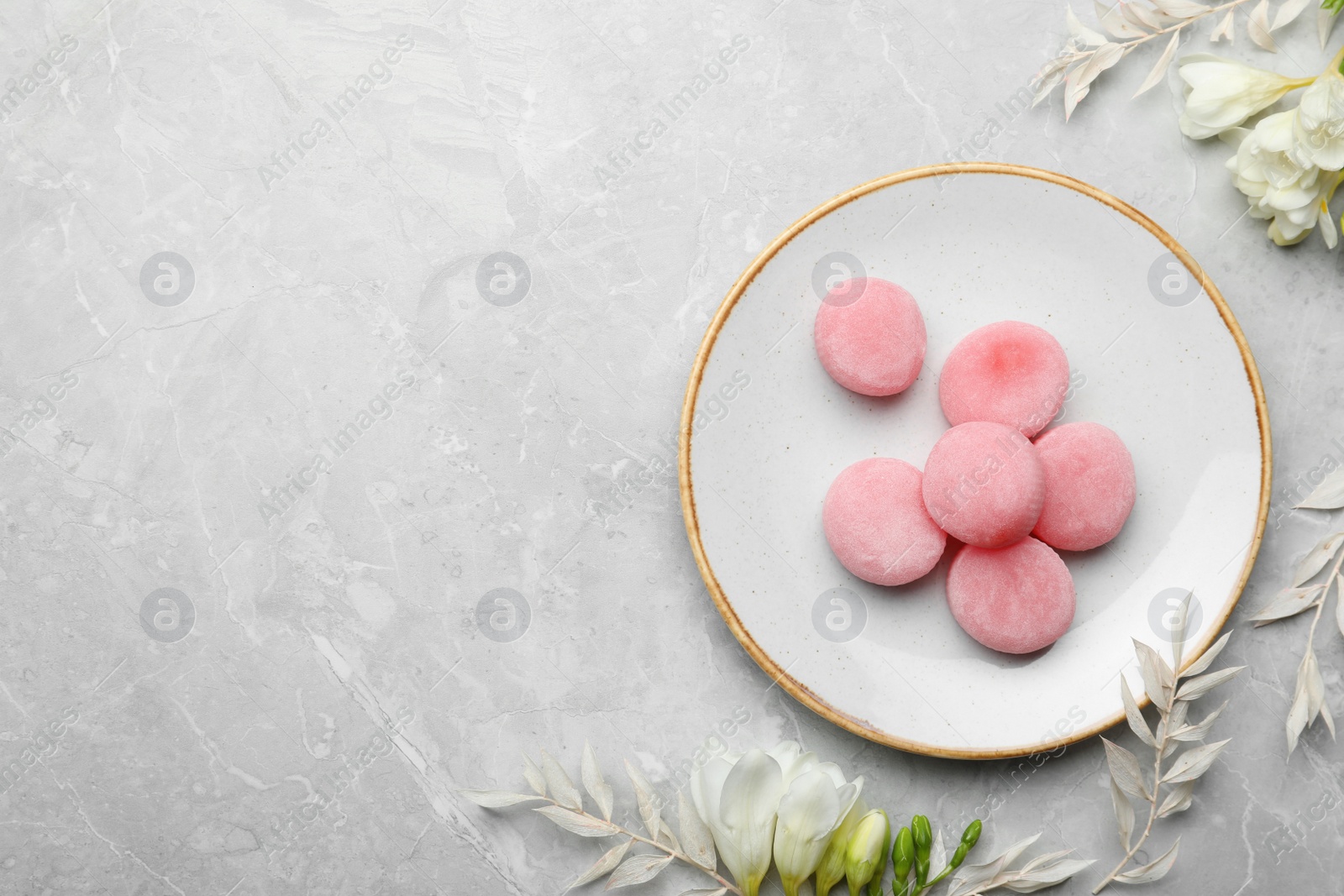 Photo of Delicious mochi and flowers on light grey marble table, flat lay with space for text. Traditional Japanese dessert