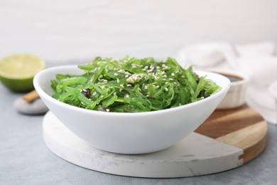 Photo of Tasty seaweed salad in bowl on gray table, closeup