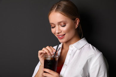 Photo of Young woman with glass of cola on black background. Refreshing drink