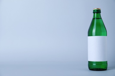 Photo of Glass bottle with soda water on light background. Space for text