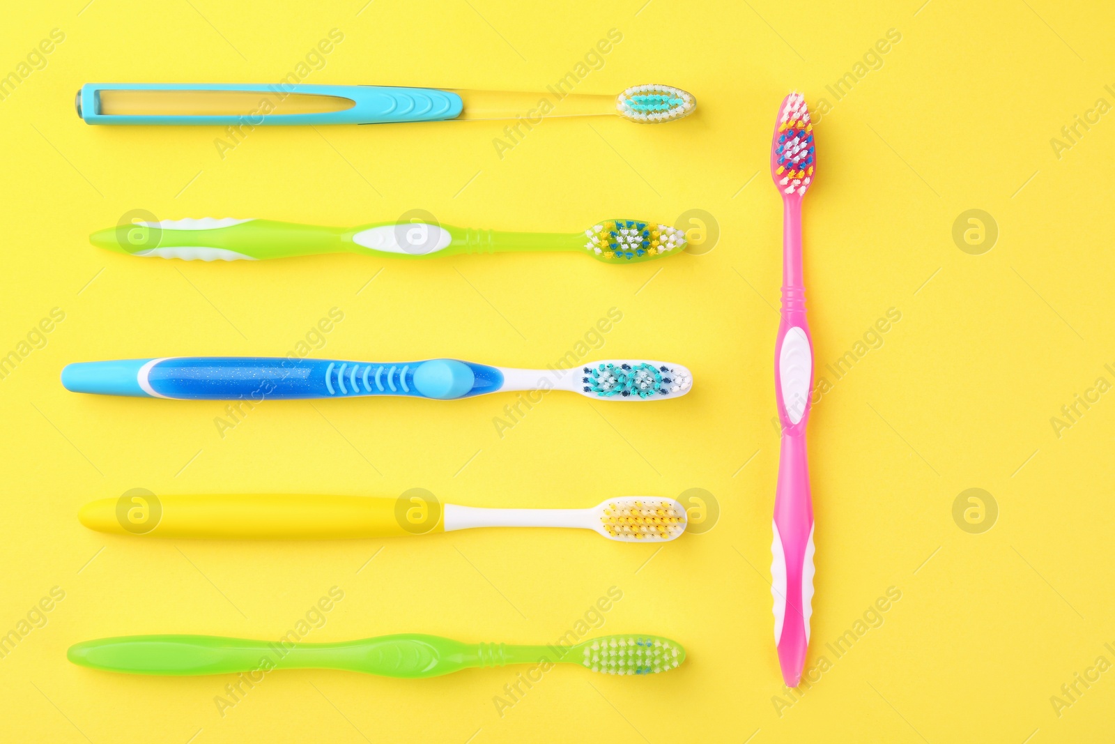 Photo of Many different toothbrushes on yellow background, flat lay