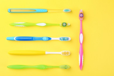 Many different toothbrushes on yellow background, flat lay