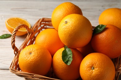 Many ripe oranges and green leaves on wooden table, closeup