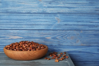 Dish with pine nuts on table against wooden background. Space for text