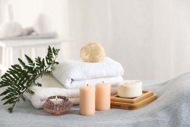 Photo of Spa composition. Burning candles, soap, towels and loofah on soft grey surface