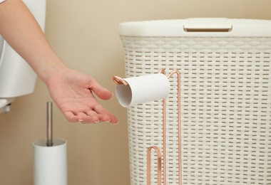 Photo of Woman reaching holder with empty toilet paper roll in bathroom, closeup