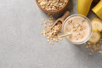 Photo of Glass of tasty banana smoothie with oatmeal on light grey table, flat lay. Space for text