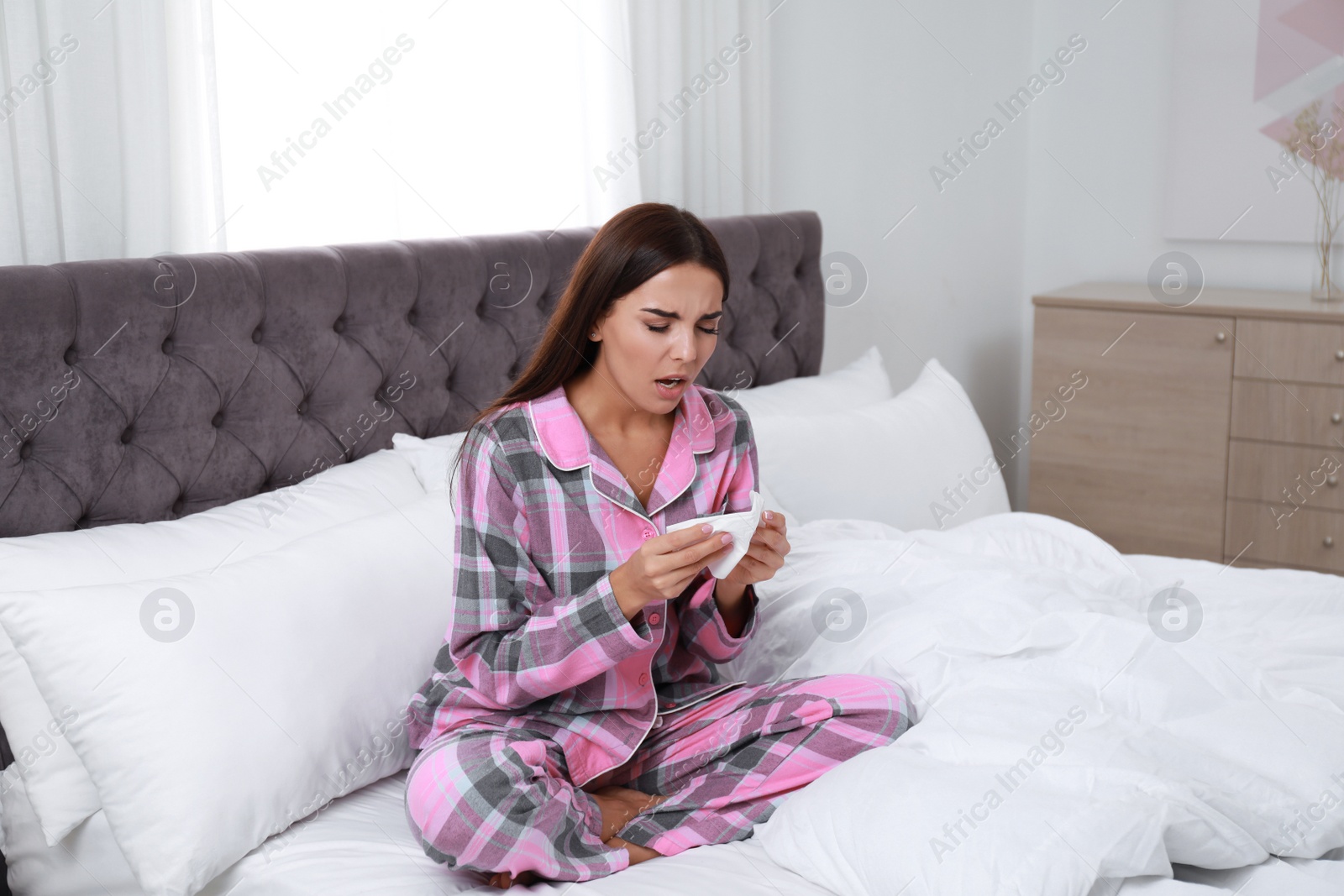 Photo of Young woman suffering from allergy in bedroom