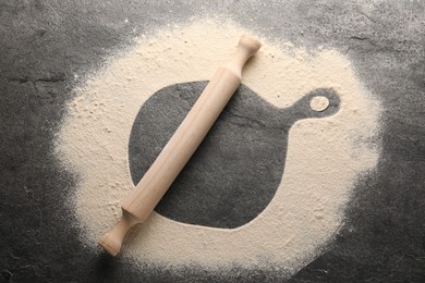 Photo of Imprint of board on grey textured table with flour and rolling pin, top view