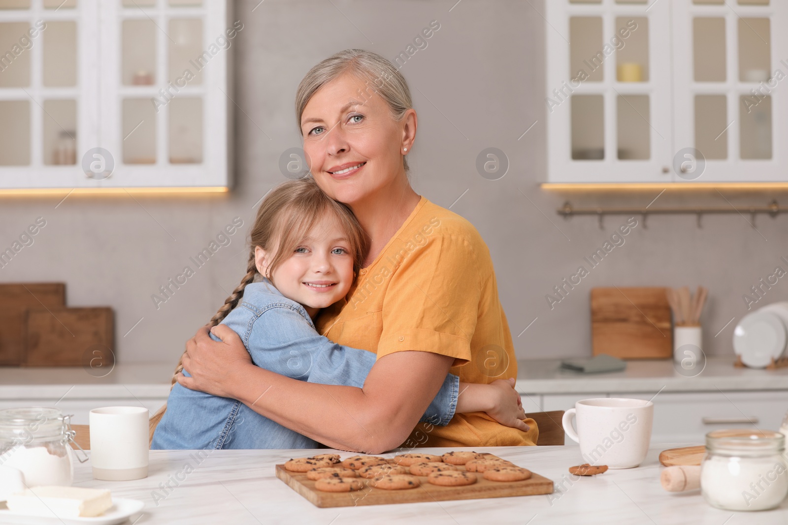 Photo of Happy grandmother hugging her granddaughter in kitchen