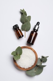 Photo of Aromatherapy products. Bottles of essential oil, sea salt and eucalyptus leaves on white background, flat lay
