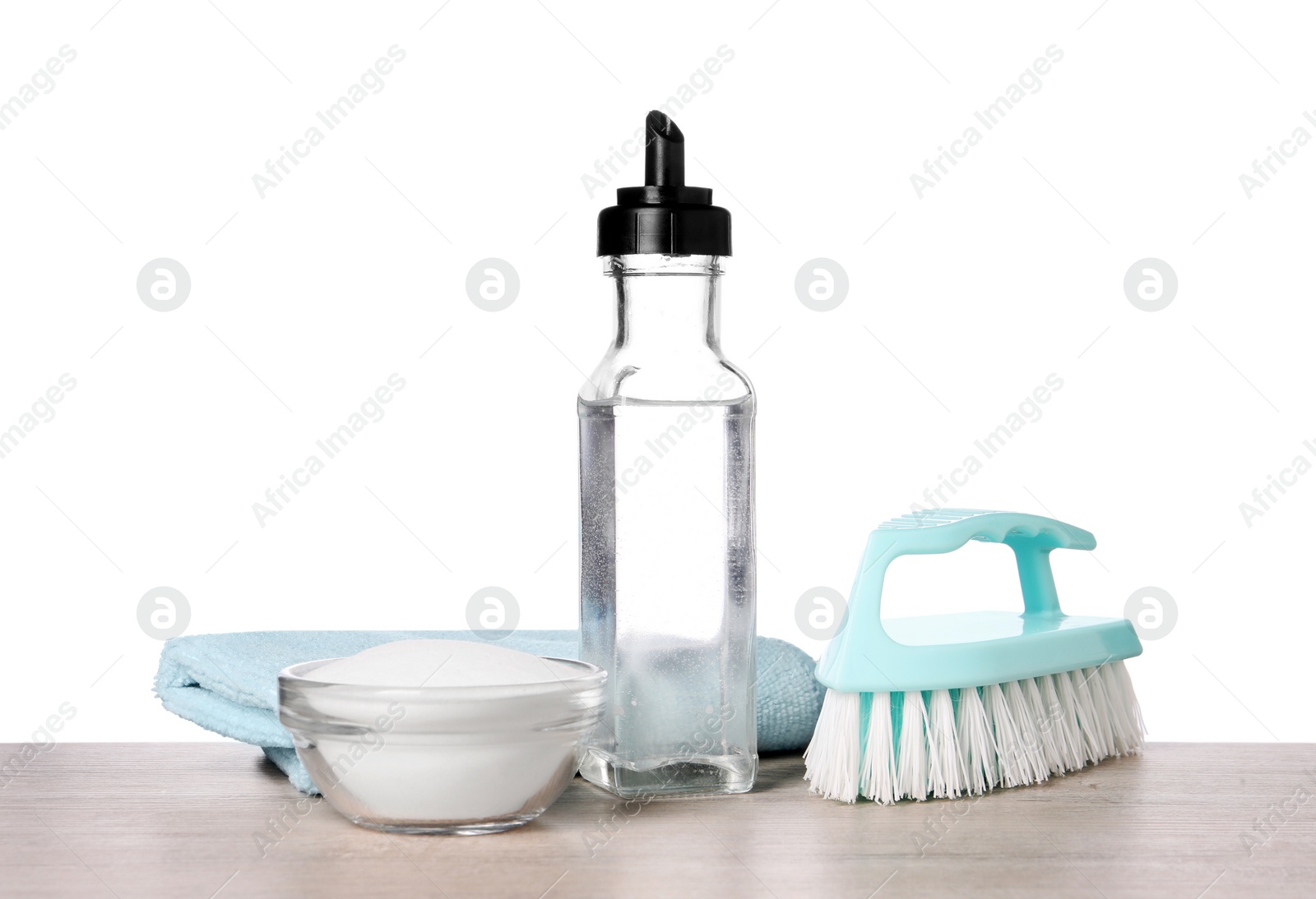 Photo of Natural cleaning products. Vinegar in bottle, baking soda, brush and rag on light wooden table against white background