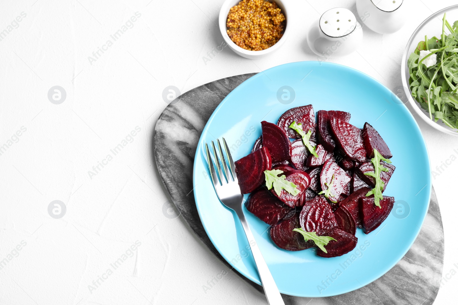 Photo of Roasted beetroot slices with arugula served on white table, flat lay. Space for text