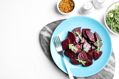 Roasted beetroot slices with arugula served on white table, flat lay. Space for text