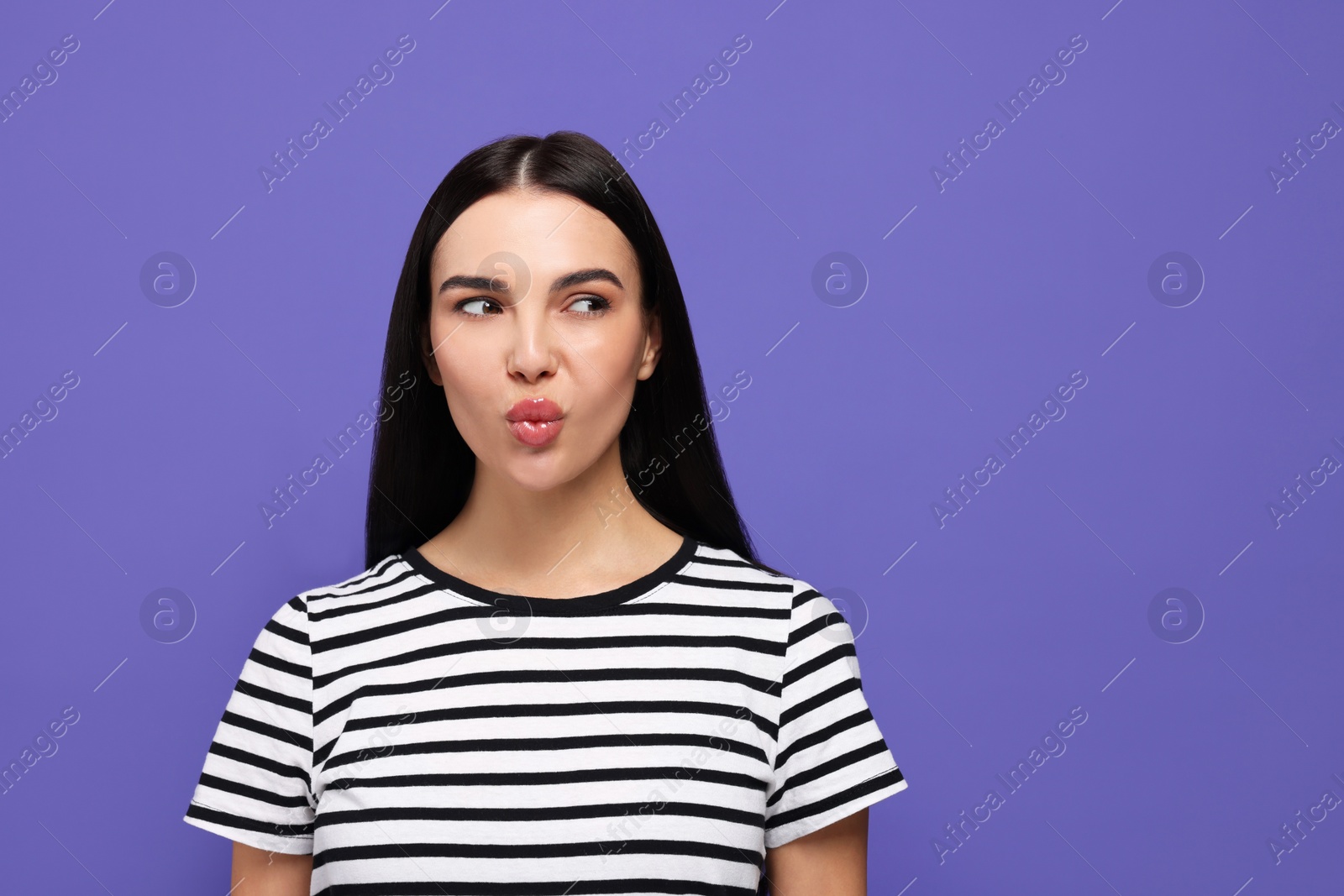 Photo of Beautiful young woman blowing kiss on purple background