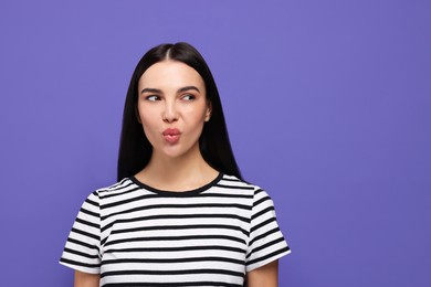 Photo of Beautiful young woman blowing kiss on purple background