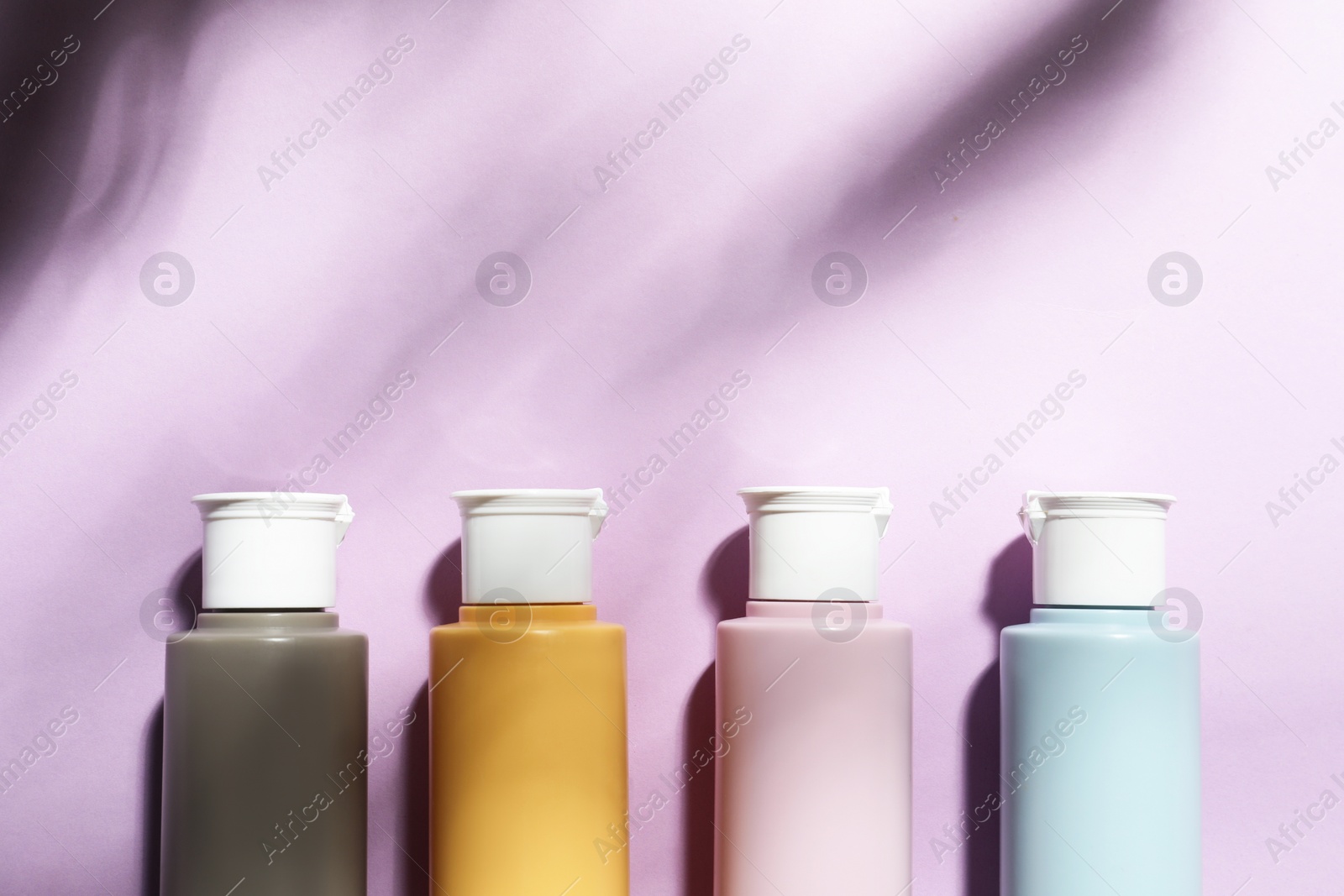 Photo of Cosmetic travel kit on violet background, top view. Space for text