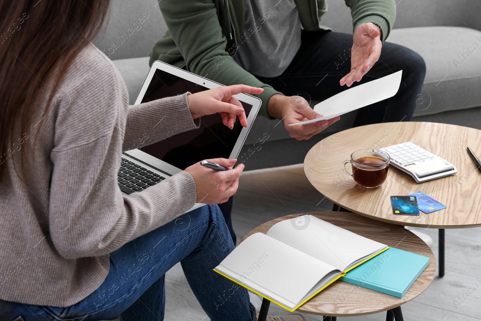 Photo of Young couple discussing family budget at table indoors, closeup