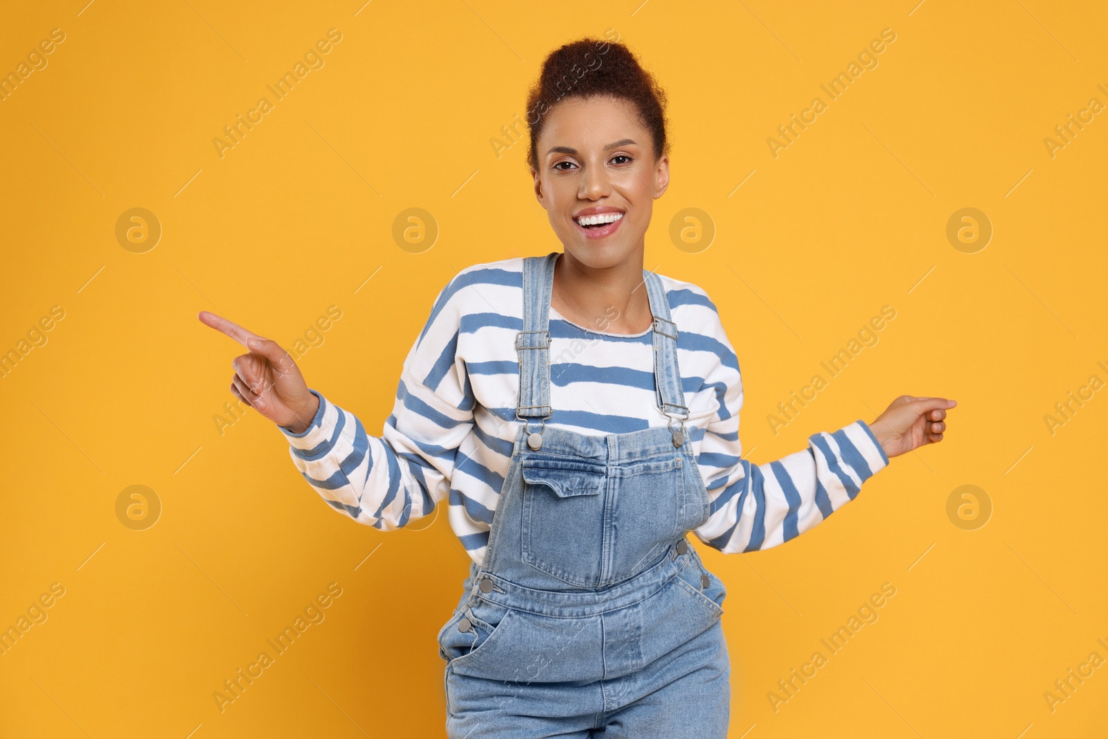 Photo of Happy young woman dancing on orange background