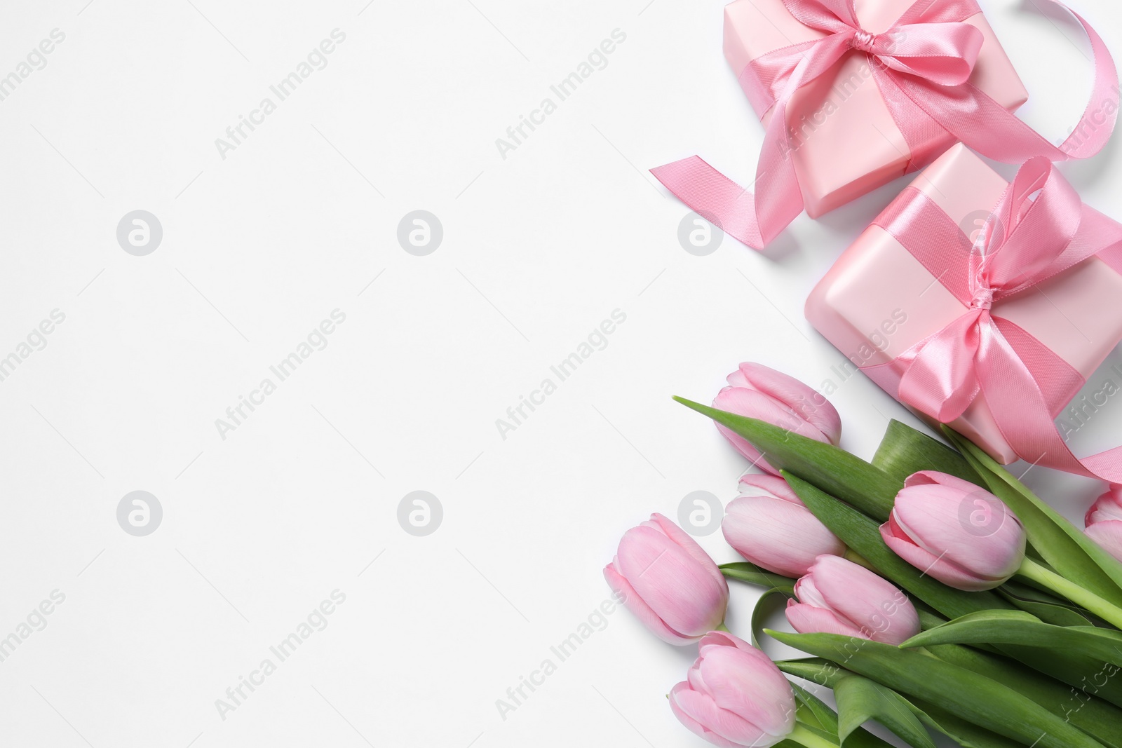 Photo of Beautiful gift boxes and pink tulip flowers on white background, flat lay. Space for text