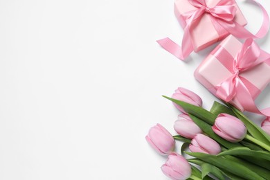 Photo of Beautiful gift boxes and pink tulip flowers on white background, flat lay. Space for text