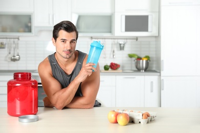 Photo of Young athletic man with ingredients for protein shake in kitchen, space for text