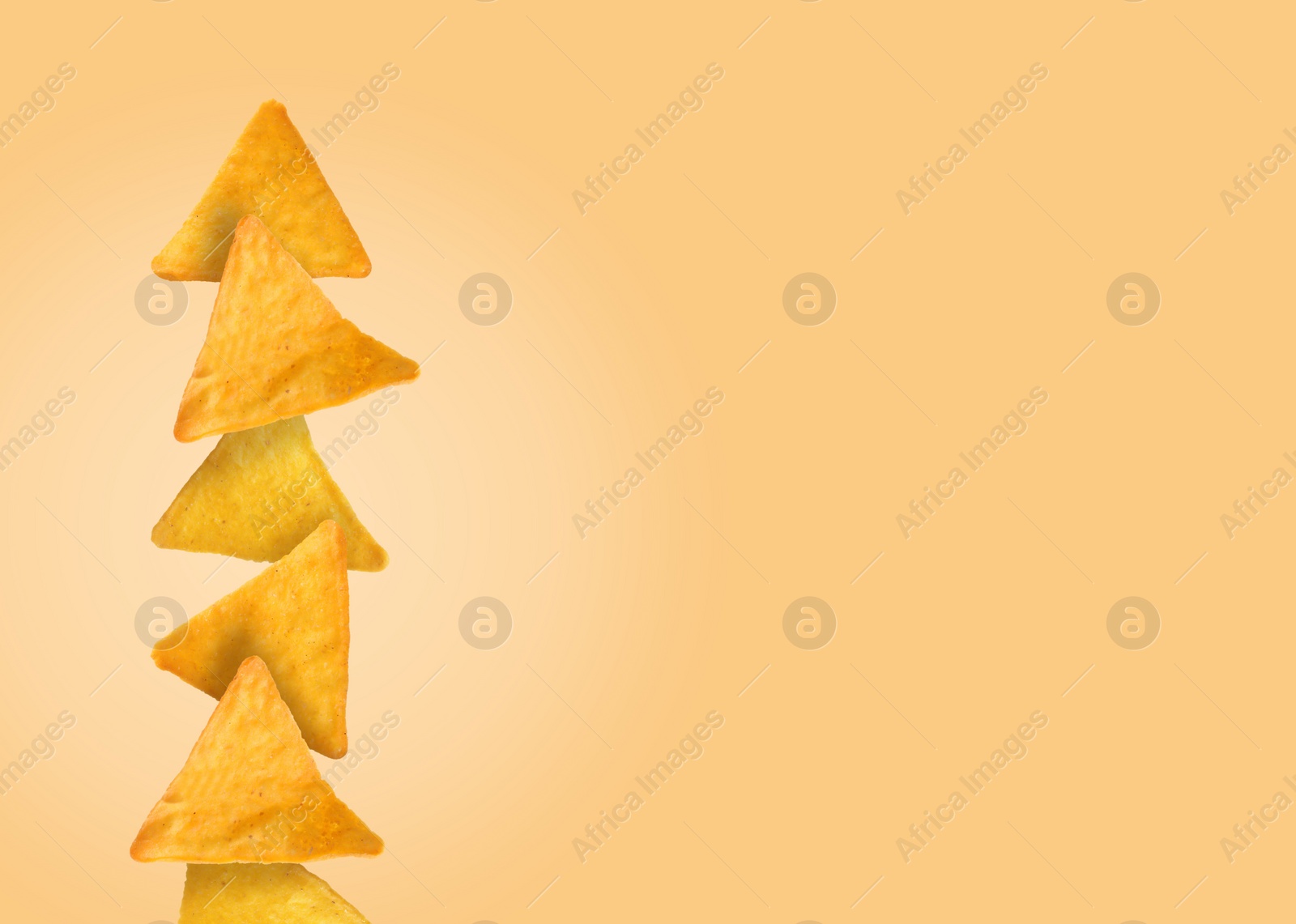 Image of Stack of tasty tortilla chips on pale light orange background, space for text