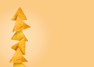 Stack of tasty tortilla chips on pale light orange background, space for text