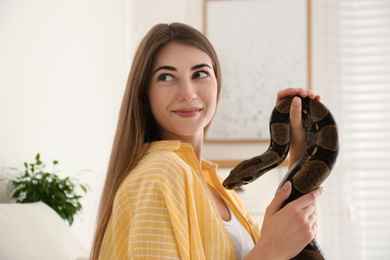 Young woman with boa constrictor at home. Exotic pet