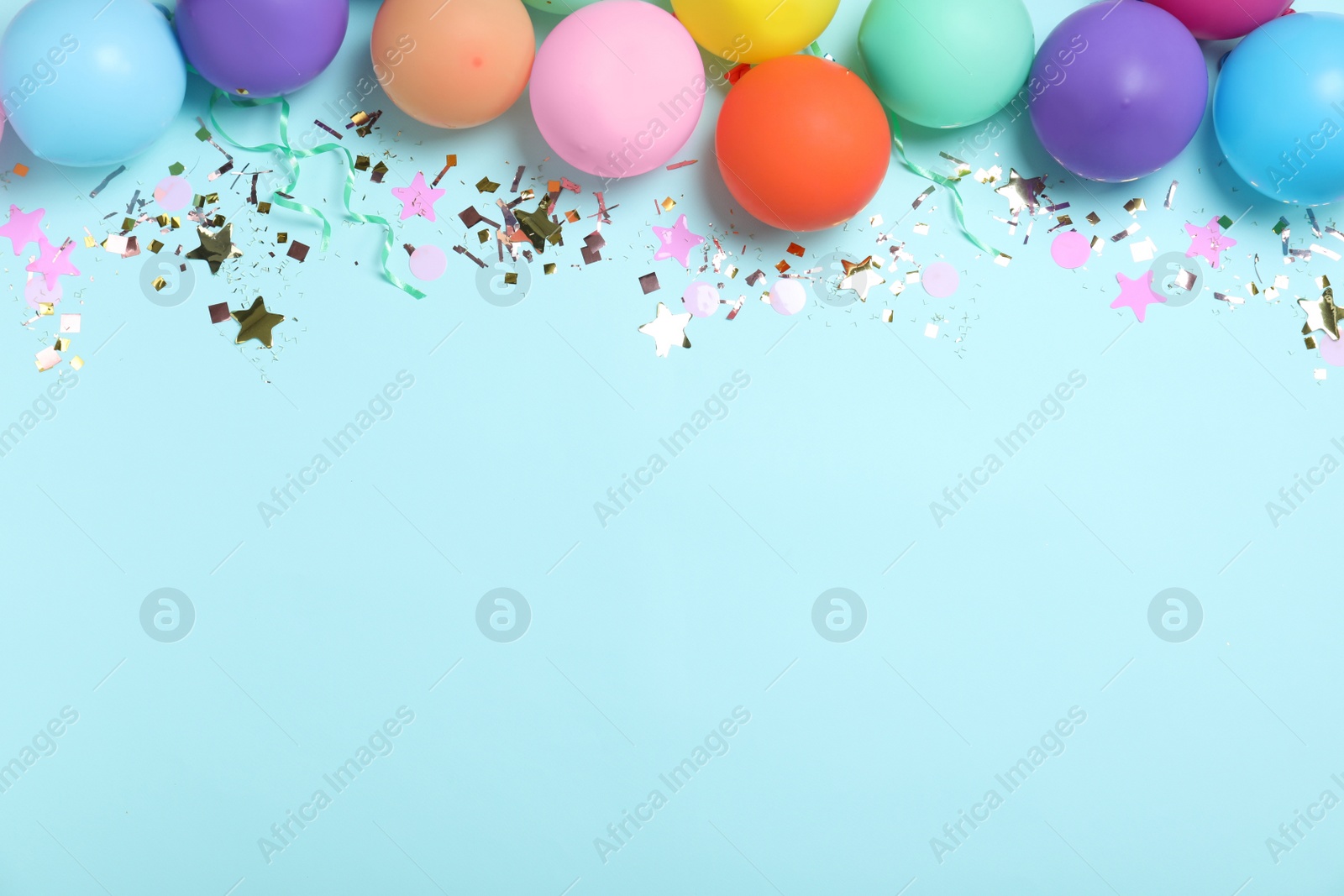 Photo of Flat lay composition with balloons and confetti on light blue background, space for text. Birthday decor
